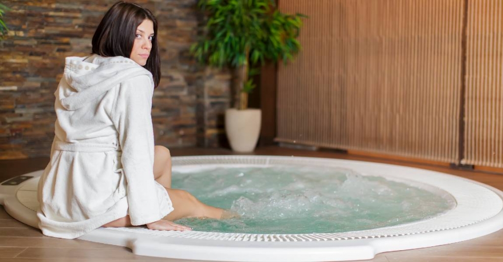 woman sits with legs in hot tub